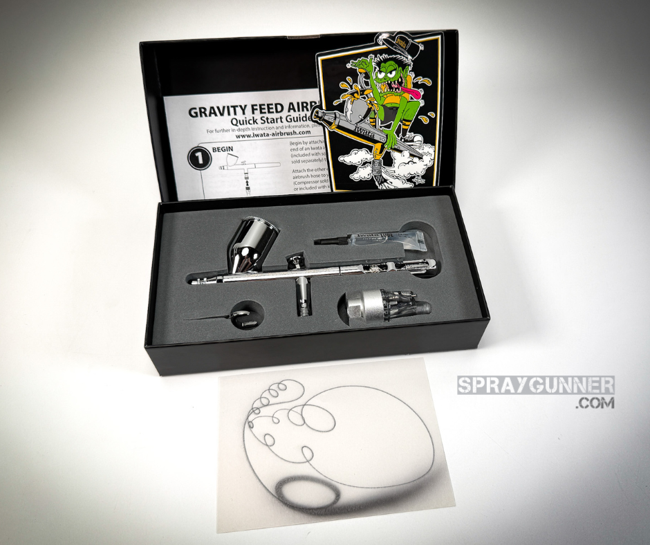 The chrome-bodied, nozzle-equipped IWATA VAULT KUSTOM CS Gravity Feed Dual Action Airbrush is open and on show in front of a branded packaging box.